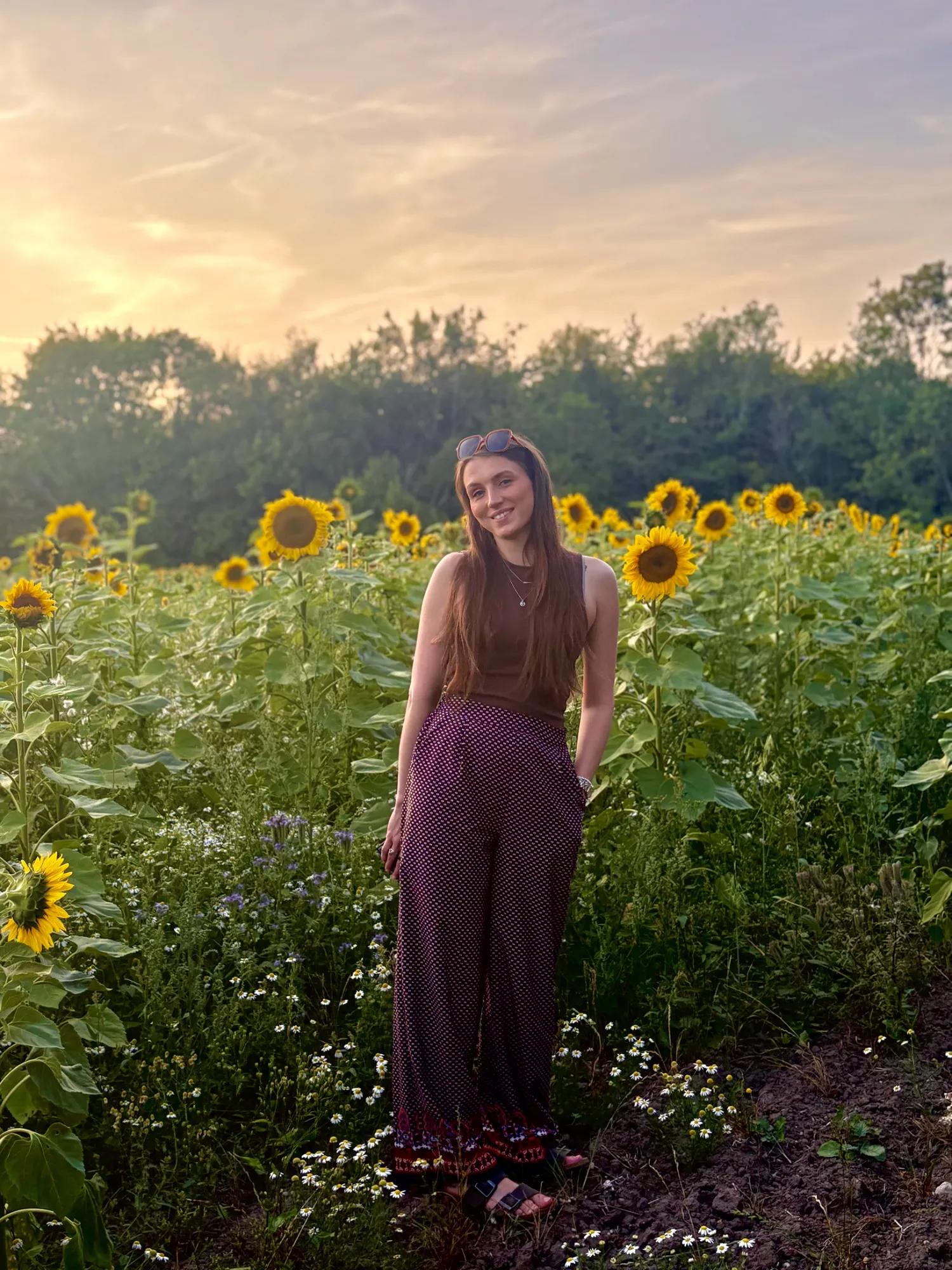 Jess smiling in a sunflower field at sunset