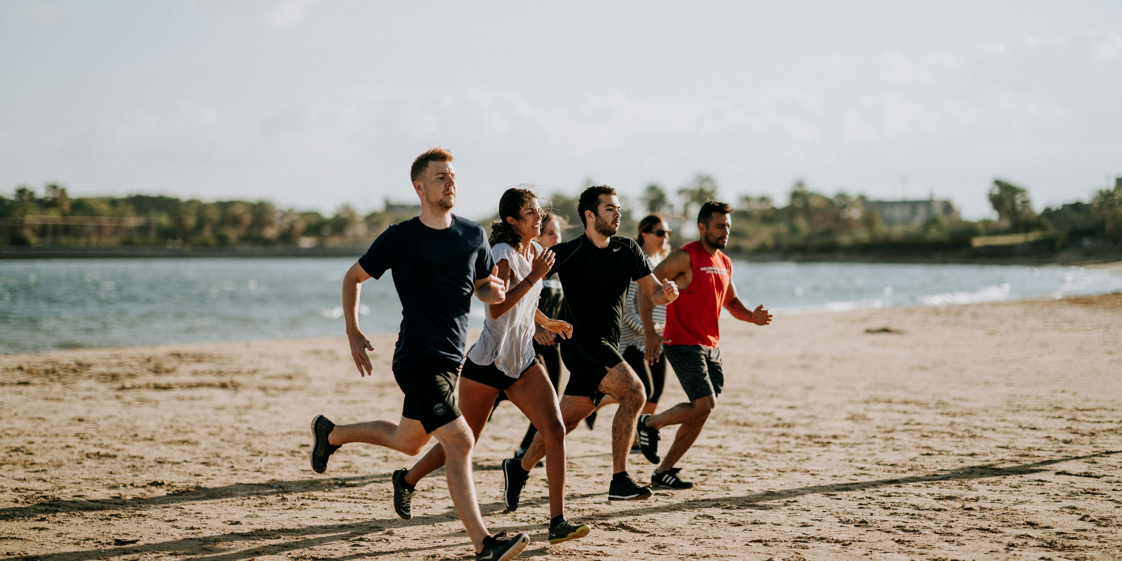 a group of people are running on the beach .