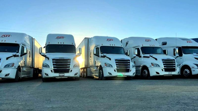 Branded semi truck fleet lined up at sunrise