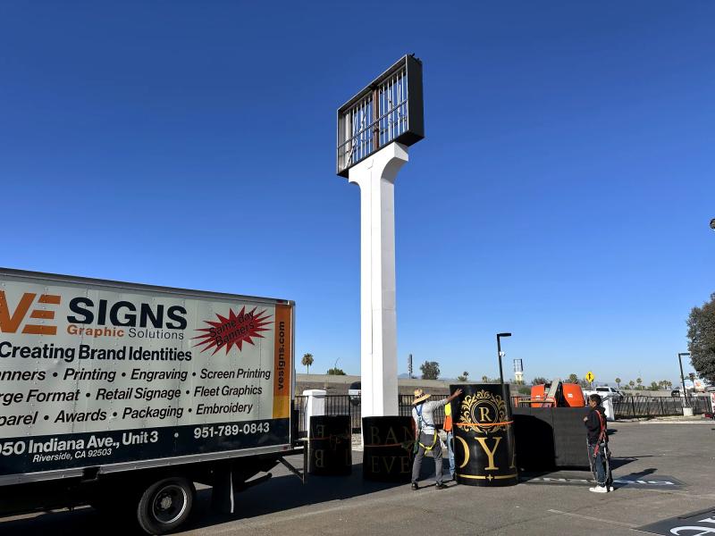 VE Signs crew installing a pylon sign with EMC display, service truck on site