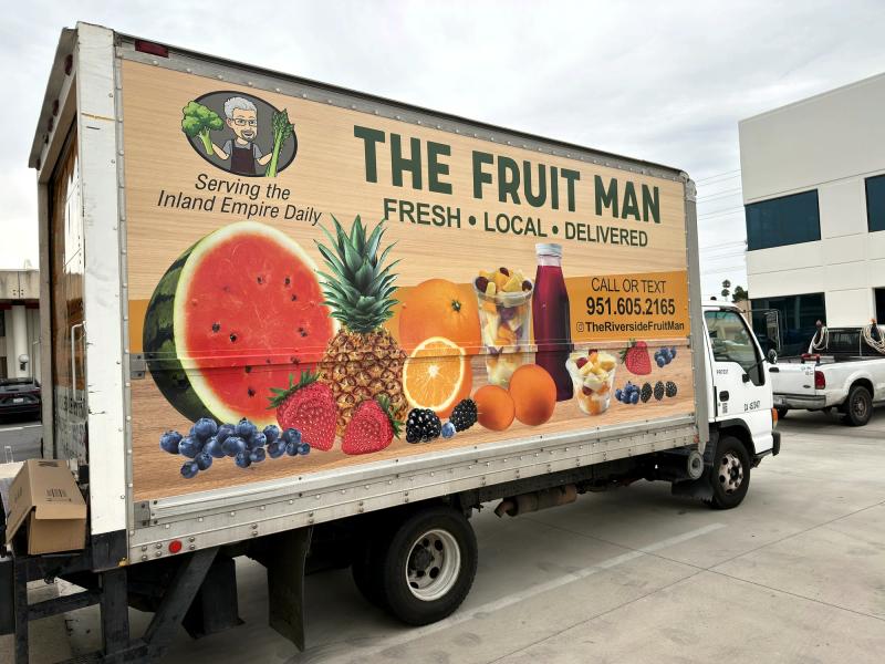Box truck wrap for The Fruit Man with vivid fruit photography, rear three-quarter view