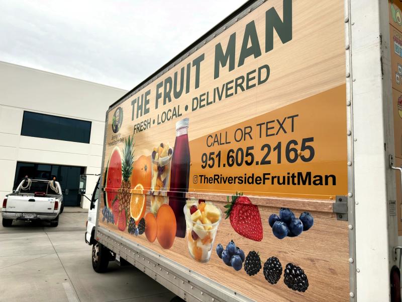 Side panel of The Fruit Man box truck wrap with contact info and fruit graphics