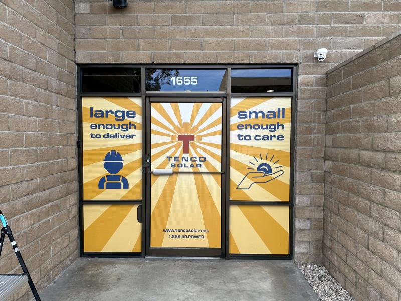 Full-coverage printed window and door graphics for Tenco Solar at a warehouse entry