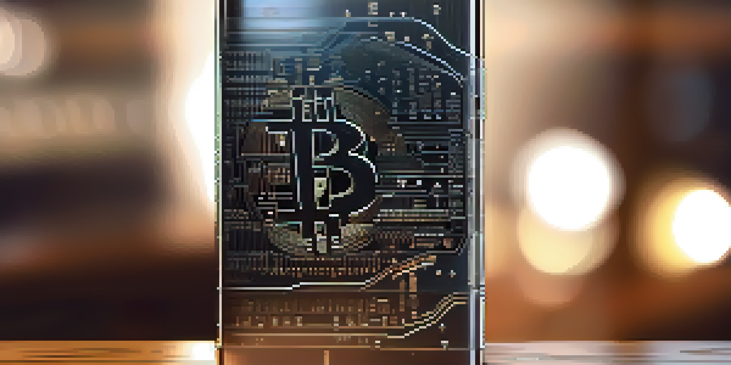 A hardware wallet on a wooden desk with a Bitcoin logo in the background.