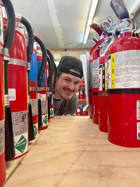 Fire extinguisher technician looking down a row of fire extinguishers.