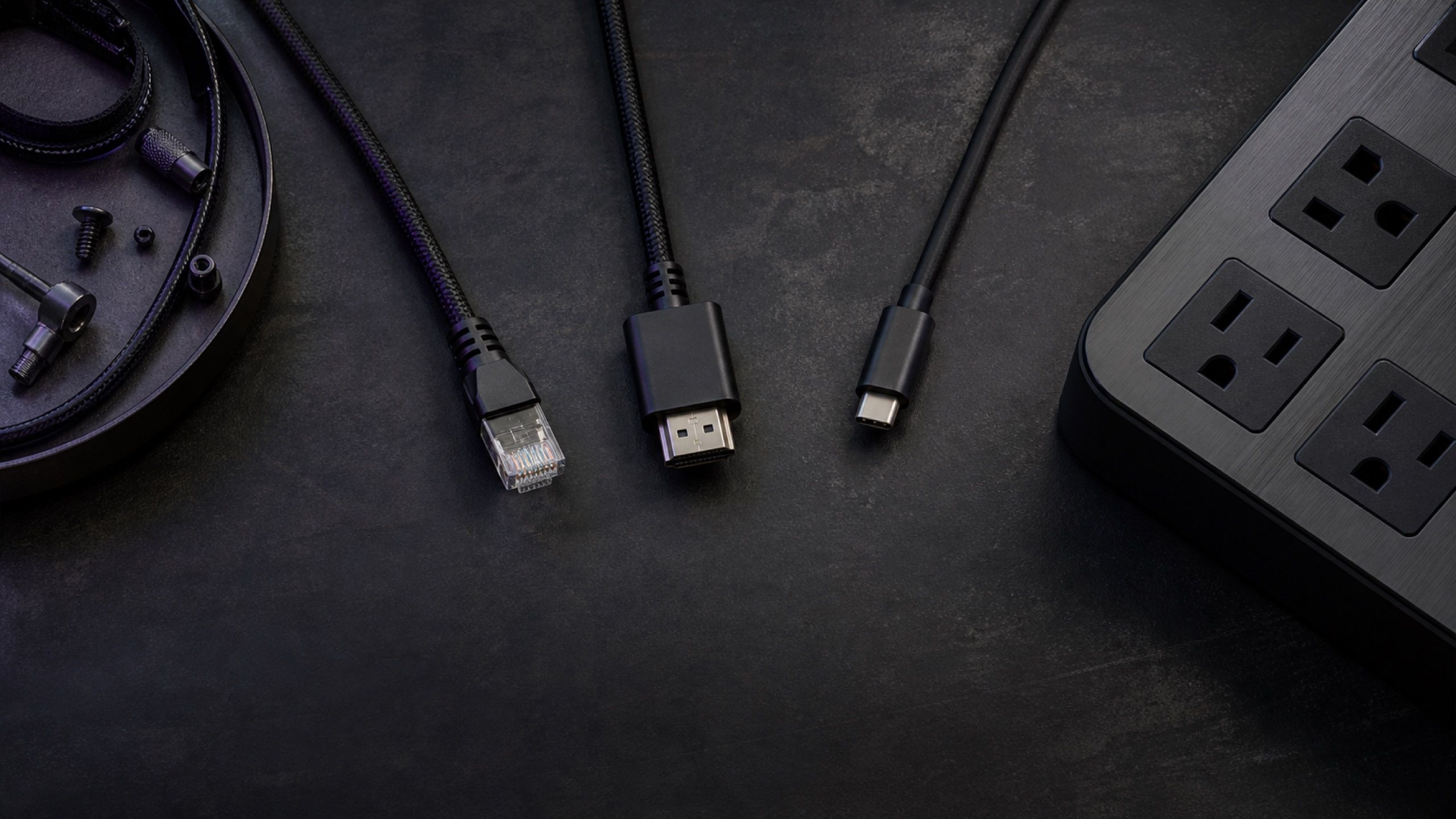 深色工作台上的 RJ45、HDMI、USB-C 線材與延長線