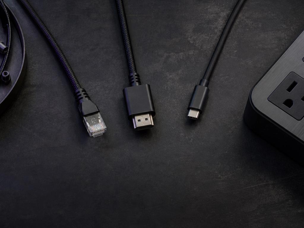 RJ45, HDMI, and USB-C cables with a power strip on a dark workbench