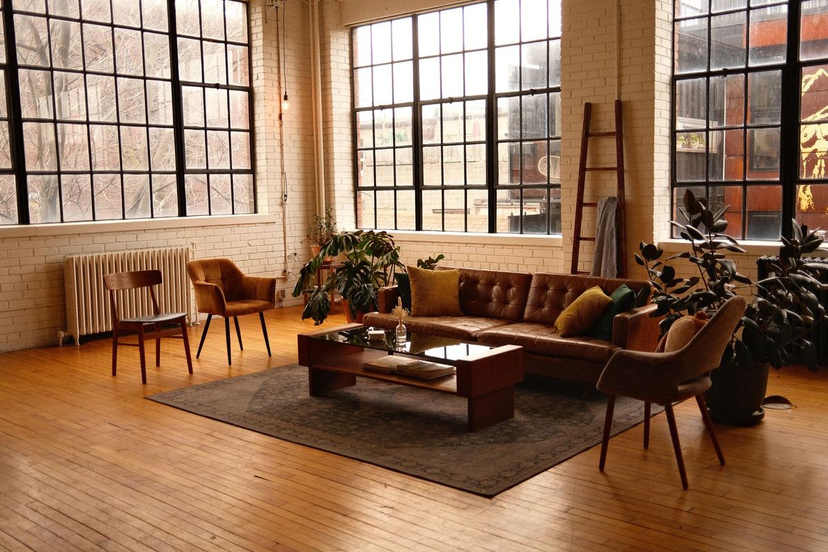 Amplia sala de estar estilo loft con muebles modernos, grandes ventanas y luz cálida.