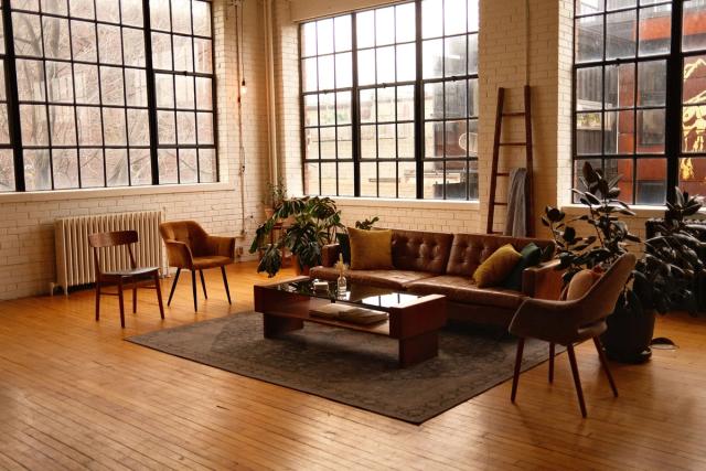 Amplia sala de estar estilo loft con muebles modernos, grandes ventanas y luz cálida.
