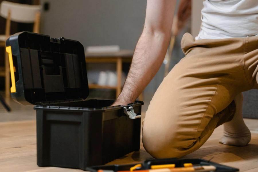 Hombre arrodillado con caja de herramientas