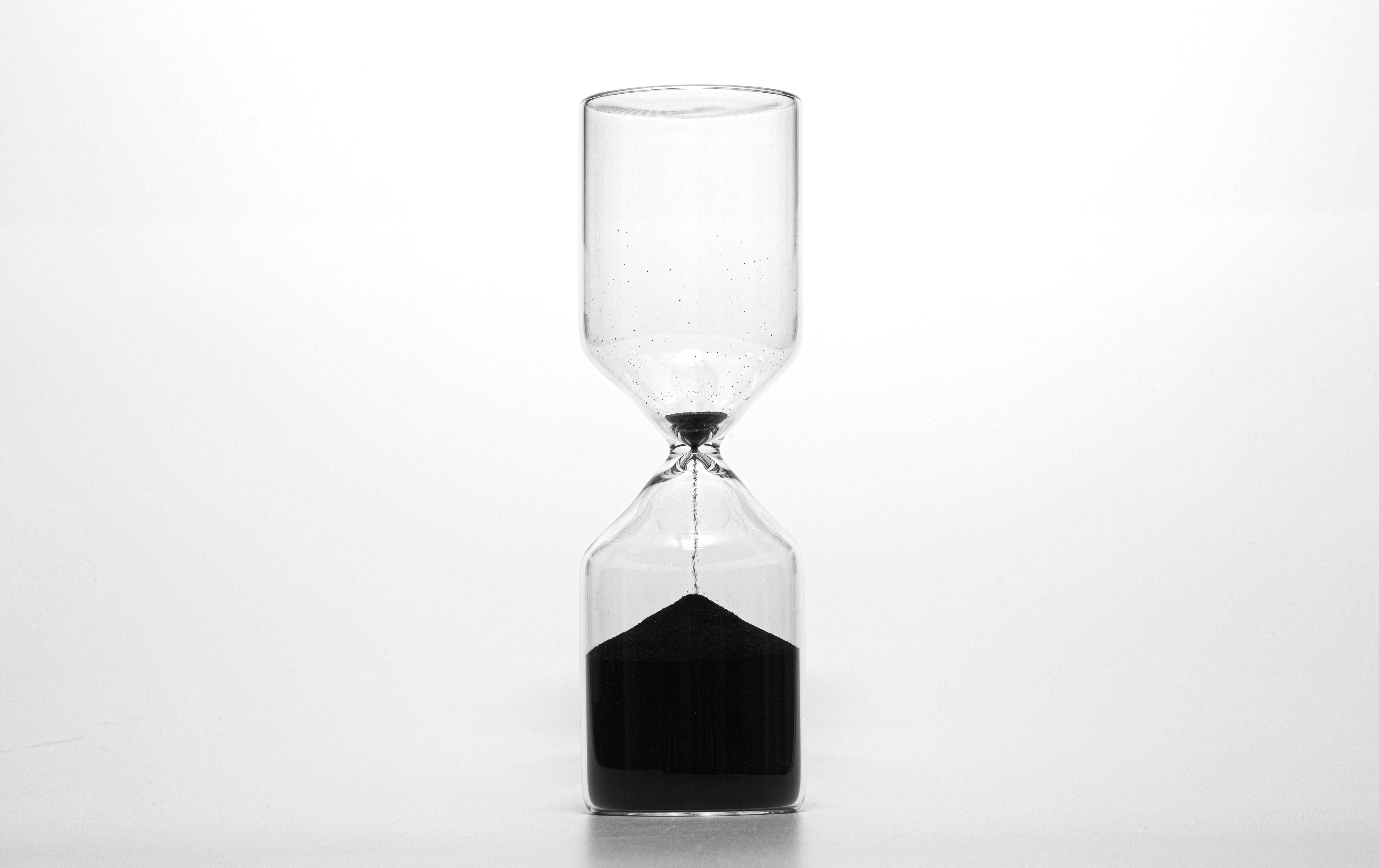 Sanduhr mit schwarzem, fast durchgelaufenem Sand als Sinnbild für Honorarmodelle nach Zeit