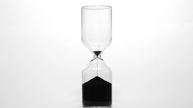 Sanduhr mit schwarzem, fast durchgelaufenem Sand als Sinnbild für Honorarmodelle nach Zeit