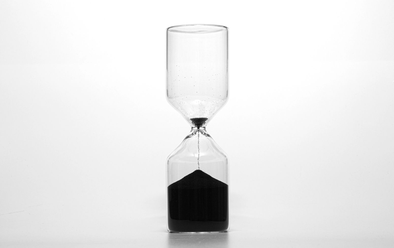 Sanduhr mit schwarzem, fast durchgelaufenem Sand als Sinnbild für Honorarmodelle nach Zeit