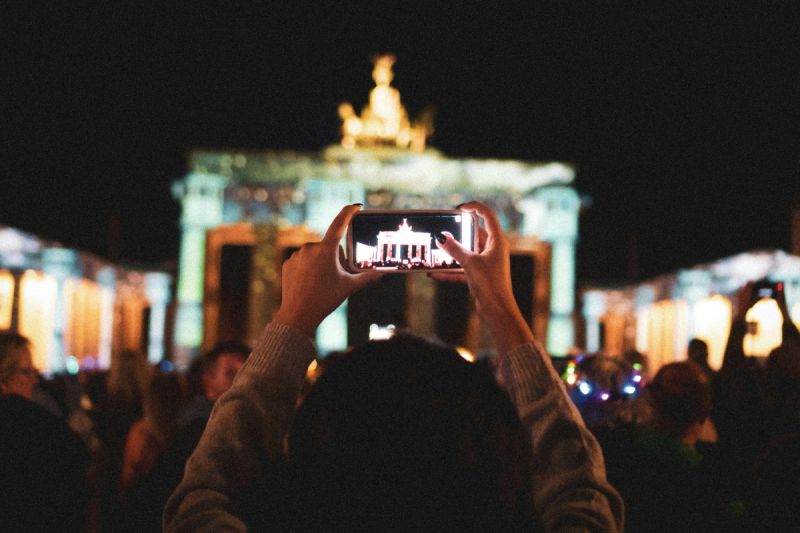 Eine Person fotografiert das Brandenburger Tor mit dem Smartphone, Sinnbild für die digitale Kommunikation in Deutschland.