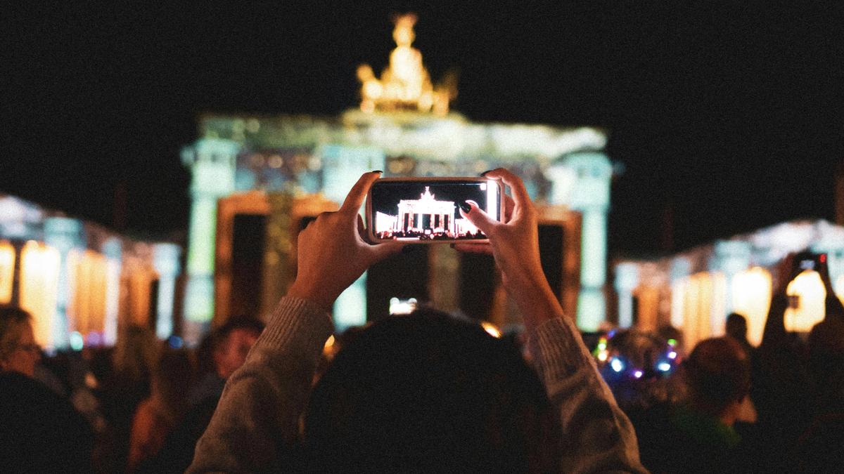 Eine Person fotografiert das Brandenburger Tor mit dem Smartphone, Sinnbild für die digitale Kommunikation in Deutschland.