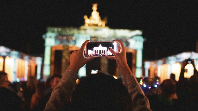 Eine Person fotografiert das Brandenburger Tor mit dem Smartphone, Sinnbild für die digitale Kommunikation in Deutschland.