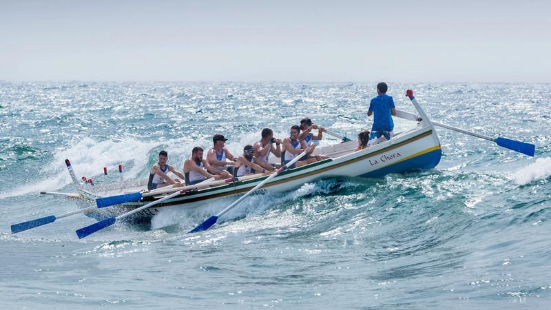 Ruderteam mit stehendem Steuermann in einem Holzboot auf bewegter See als Sinnbild für das Thema B2B-Software-Vertrieb skalieren