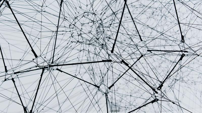 Abstraktes schwarz-weißes 3D-Drahtnetzwerk mit verbundenen Knotenpunkten, Sinnbild für Knowledge-Graph-Architektur und Multi-Agenten-Systeme in der KI-Compliance