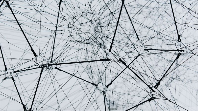 Abstract black-and-white 3D wire network with interconnected nodes, representing knowledge graph architecture and multi-agent systems in AI compliance