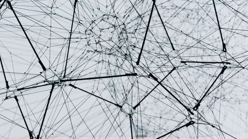 Abstraktes schwarz-weißes 3D-Drahtnetzwerk mit verbundenen Knotenpunkten, Sinnbild für Knowledge-Graph-Architektur und Multi-Agenten-Systeme in der KI-Compliance