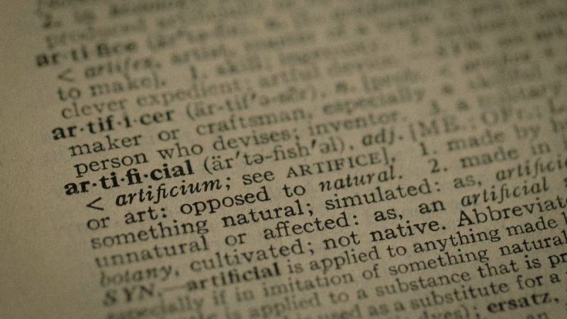 KI-Begriffe für Geschäftsführer, Wörterbucheintrag artificial als Symbol für die Sprache der künstlichen Intelligenz