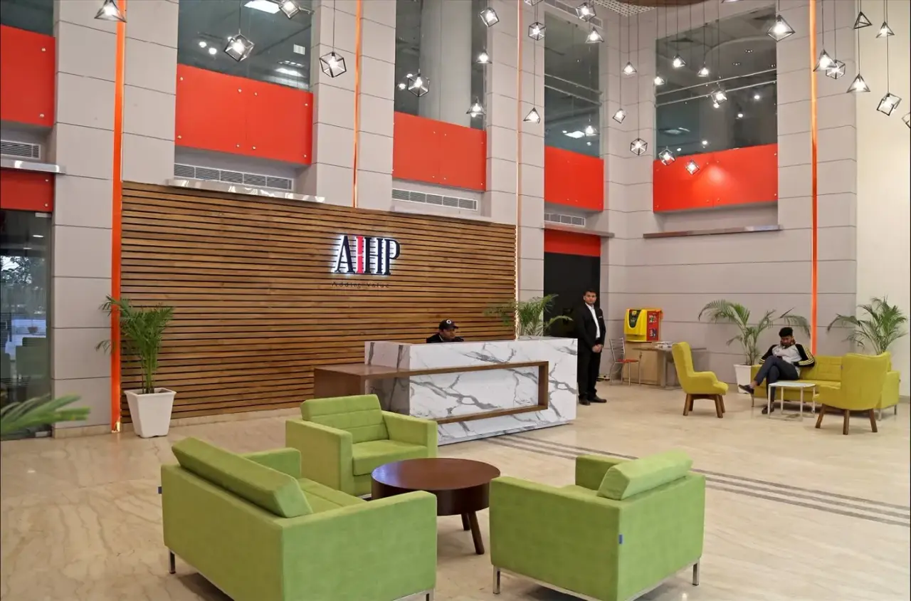 Reception with the AIHP logo on a slatted wood wall and green lounge chairs, in an AIHP managed office in Gurgaon