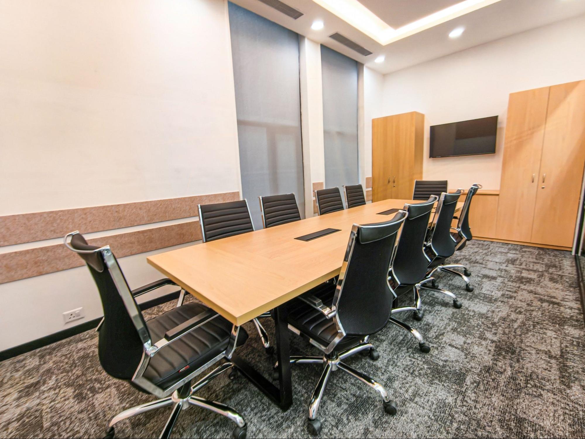 Ten-seat meeting room with a wood table, black leather chairs and a wall-mounted screen, AIHP SCO 31, Sector 32 Gurgaon