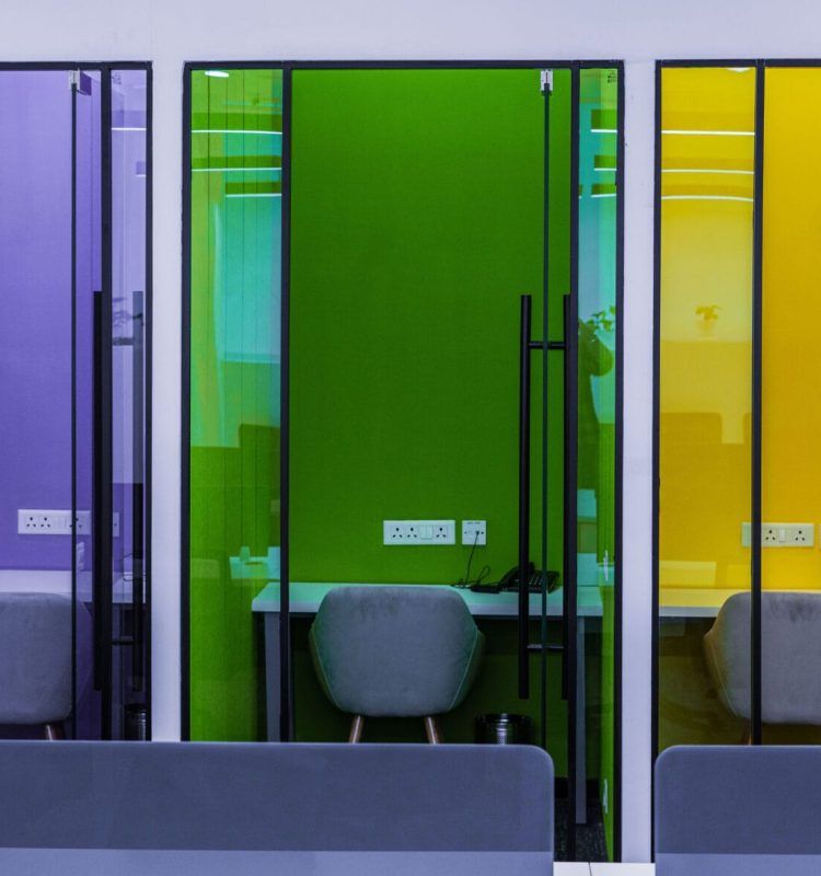 Glass-fronted single-seat phone booths with purple, green and yellow tinted doors, AIHP Palms, Udyog Vihar Gurgaon