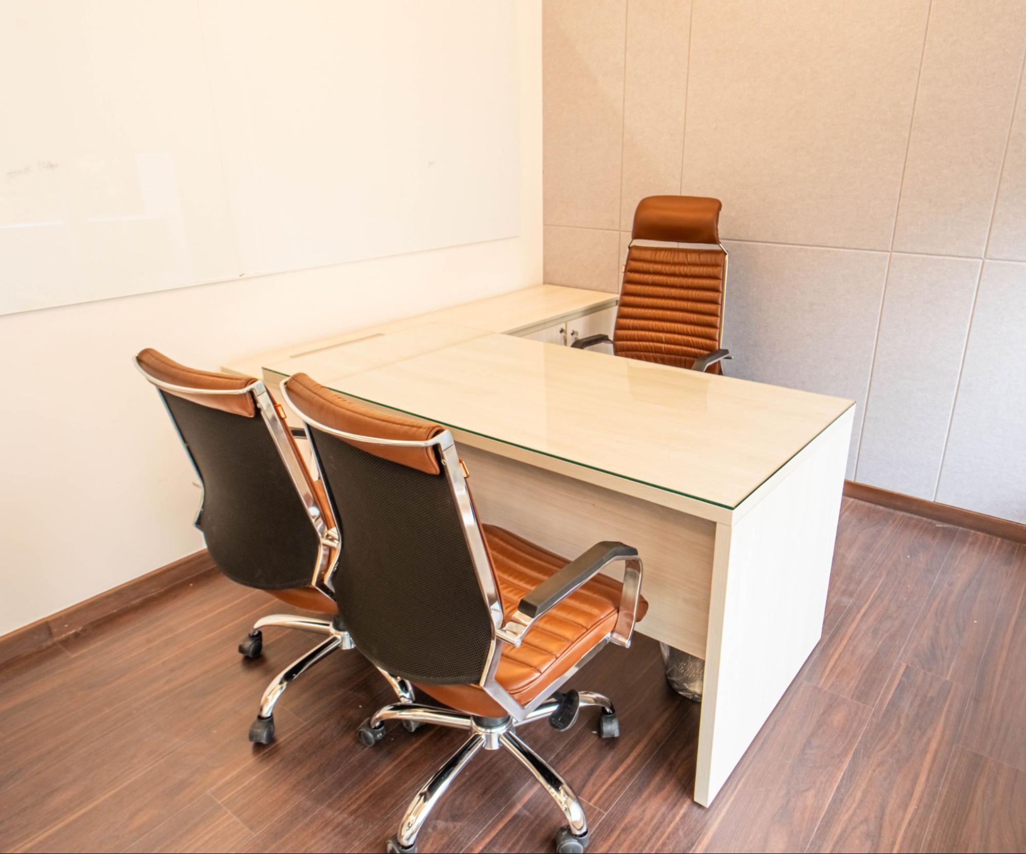 Private cabin with a white desk and tan leather chairs, AIHP SCO 34, Sector 32 Gurgaon