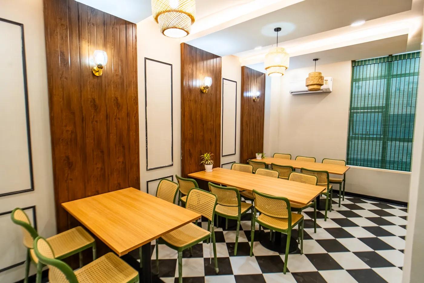 AIHP Atrium café and breakout dining area with wood tables and checkerboard flooring, Sector 32 Gurgaon