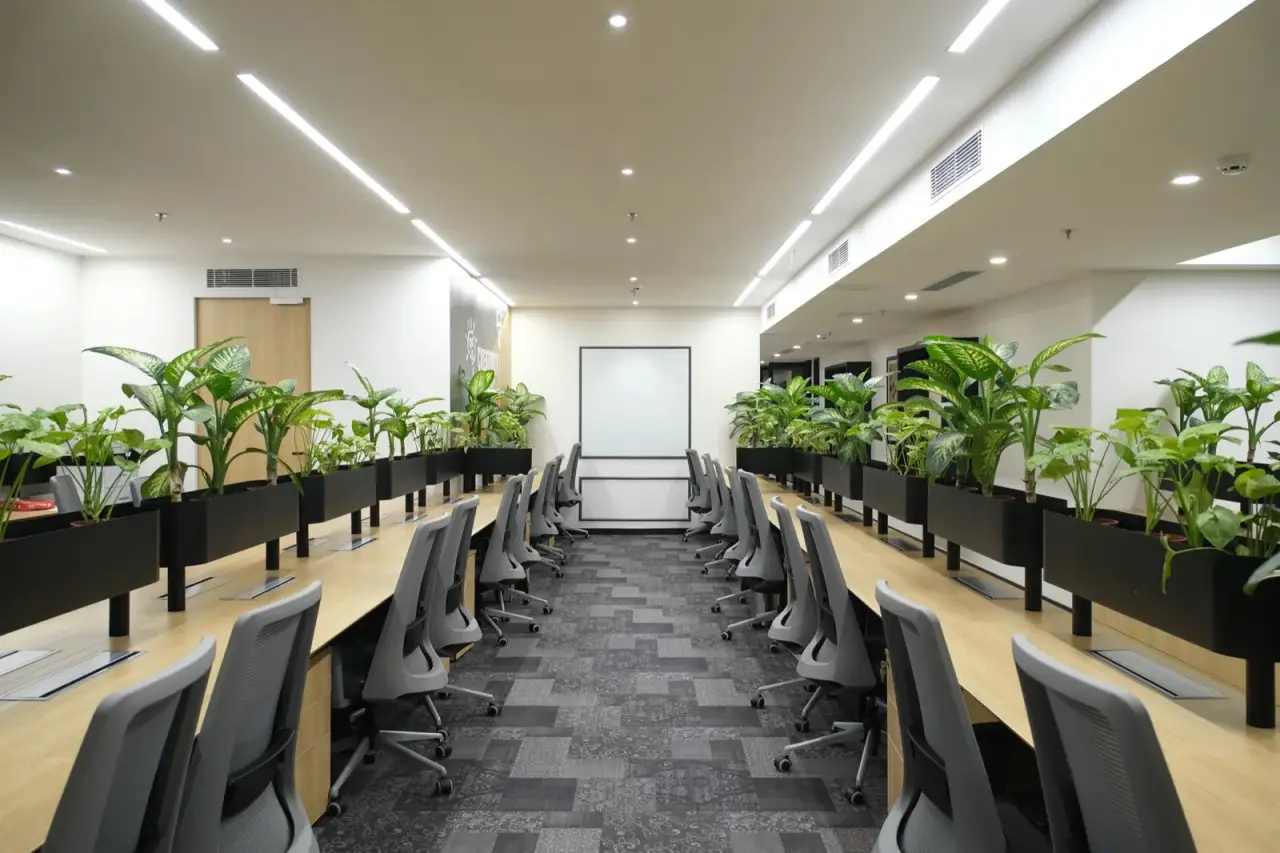 Long rows of workstations with planter dividers facing a whiteboard at AIHP Milestone, Udyog Vihar, Gurgaon