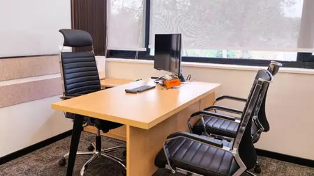 Private cabin with a wood desk, leather chairs, monitor and whiteboard by a tree-facing window, AIHP SCO 31, Sector 32 Gurgaon