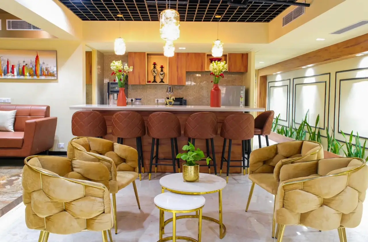 Café and breakout area with yellow upholstered chairs, round tables and a coffee counter, in an AIHP managed office in Gurgaon