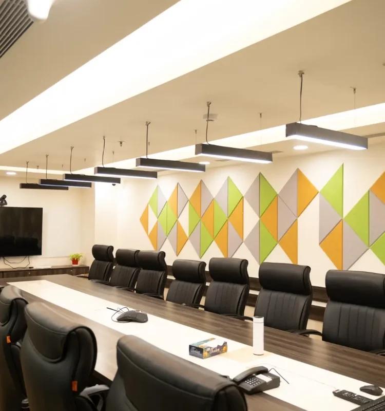 Long boardroom with executive leather chairs, geometric green and orange acoustic wall and wall TV, AIHP Horizon, Udyog Vihar Gurgaon