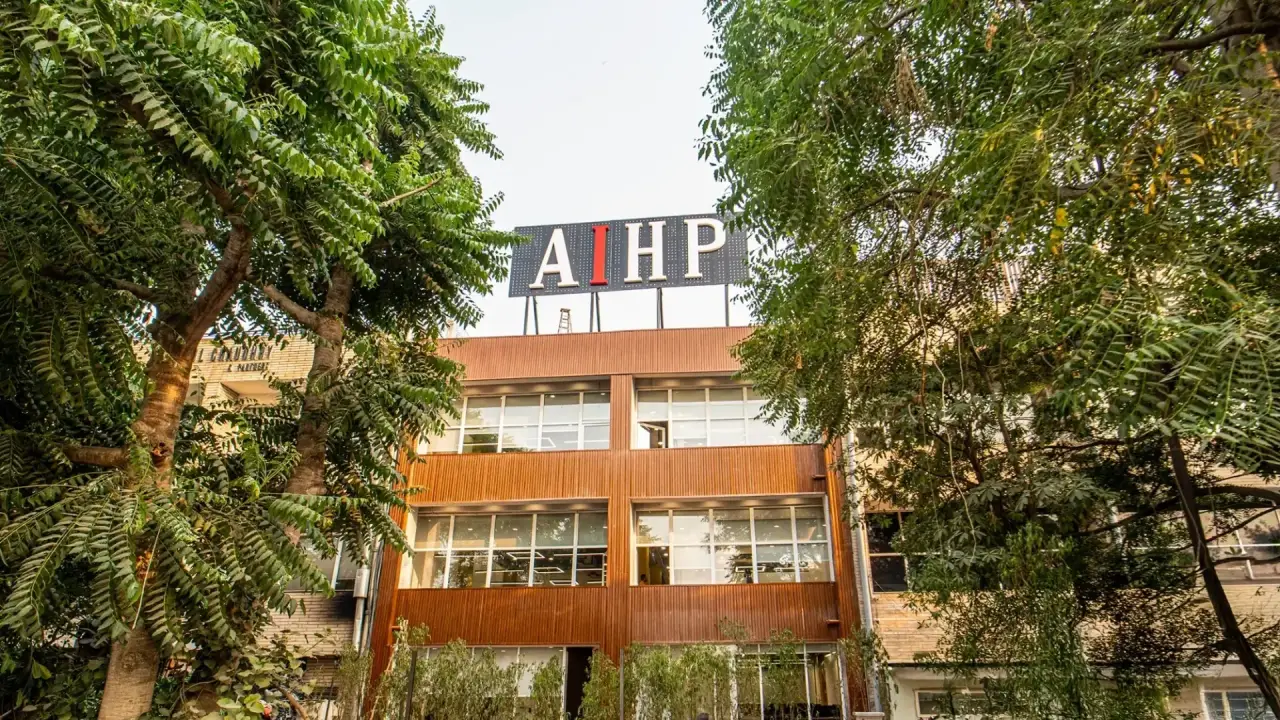 AIHP SCO 27 building facade with rooftop signage seen through tree canopy