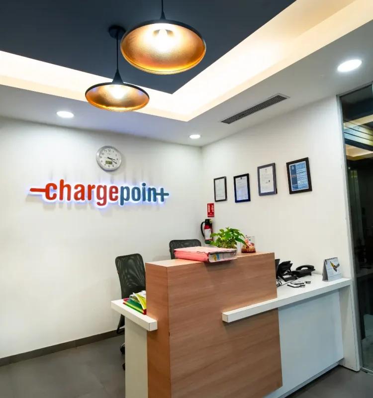 ChargePoint tenant reception desk under copper pendant lights with framed certificates, AIHP Signature, Udyog Vihar Gurgaon
