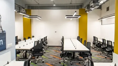 Meeting room at AIHP SCO 27 with long white tables, black chairs and yellow accent walls