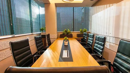 Meeting room with a wooden conference table, leather chairs and windows overlooking greenery