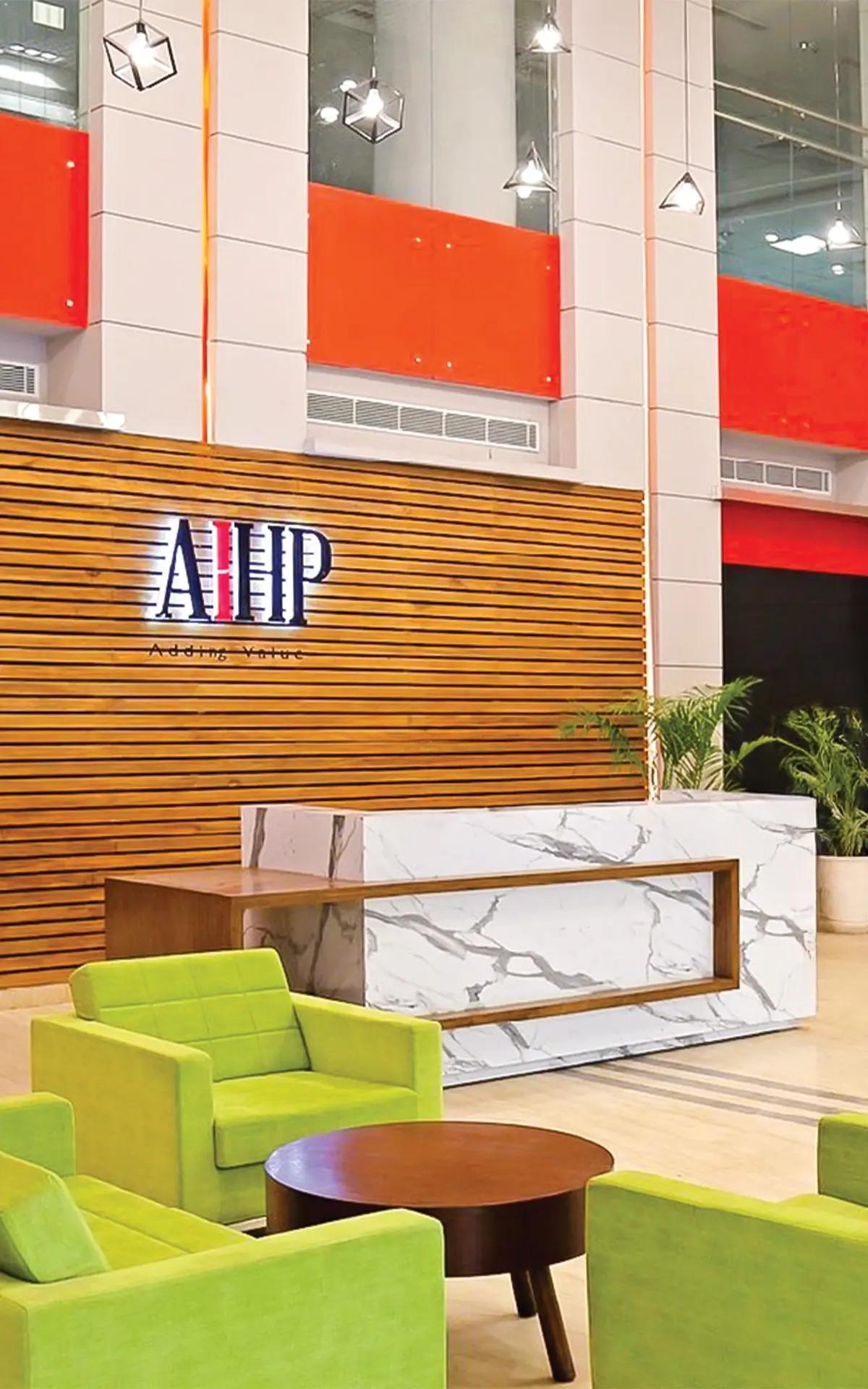 AIHP reception with wood-slat signage wall, marble desk, and lime-green lounge seating