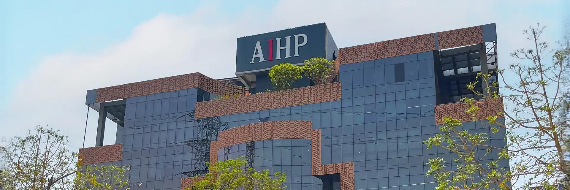 AIHP Milestone glass-and-brick office tower facade with rooftop branding, NH-8 Udyog Vihar Phase V, Gurgaon
