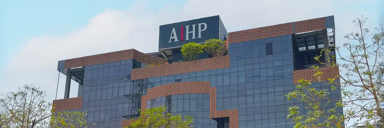 AIHP Milestone glass-and-brick office tower facade with rooftop branding, NH-8 Udyog Vihar Phase V, Gurgaon