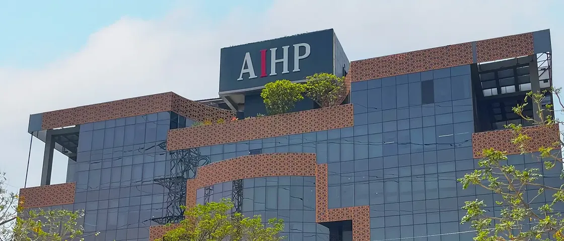 AIHP Milestone glass-and-brick office tower facade with rooftop branding, NH-8 Udyog Vihar Phase V, Gurgaon