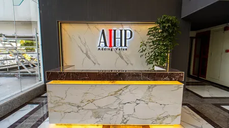 AIHP Atrium reception desk with backlit marble brand wall and the AIHP 'Adding Value' logo, Sector 32 Gurgaon