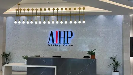 Reception desk with illuminated AIHP logo and gold pendant lighting at AIHP Palms