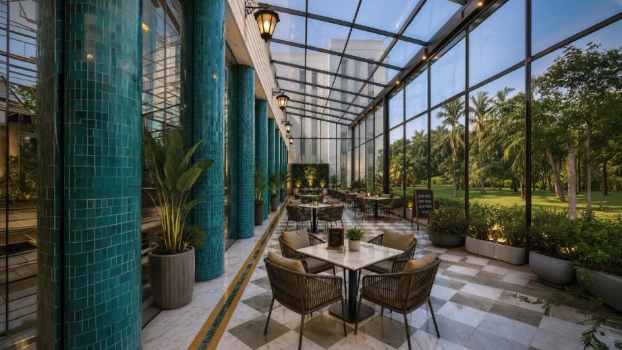 Outdoor dining conservatory under a glass roof opening onto the gardens at AIHP Imperial, Sector 32 Gurgaon