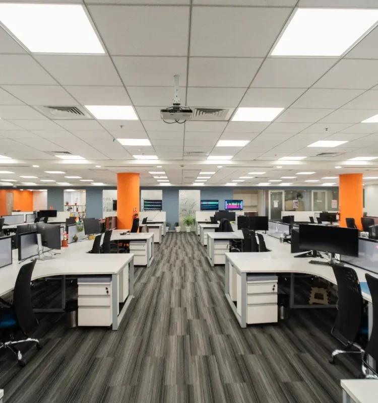 Open-plan workstation floor with rows of desks and orange accent columns at AIHP Signature