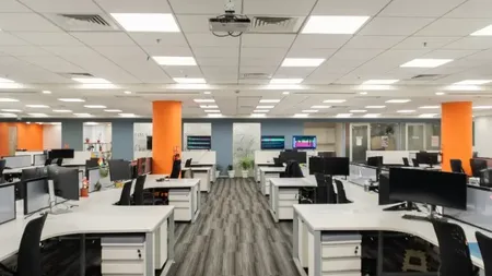 Open-plan workstation floor with rows of desks and orange accent columns at AIHP Signature