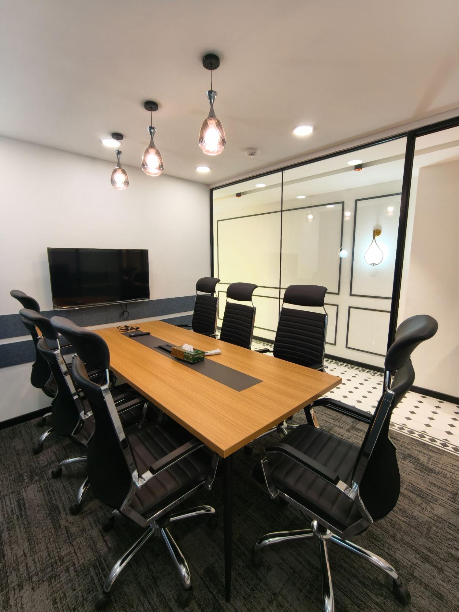 Meeting room with wall-mounted screen, wood table and black leather chairs, AIHP SCO 29B, Sector 32 Gurgaon