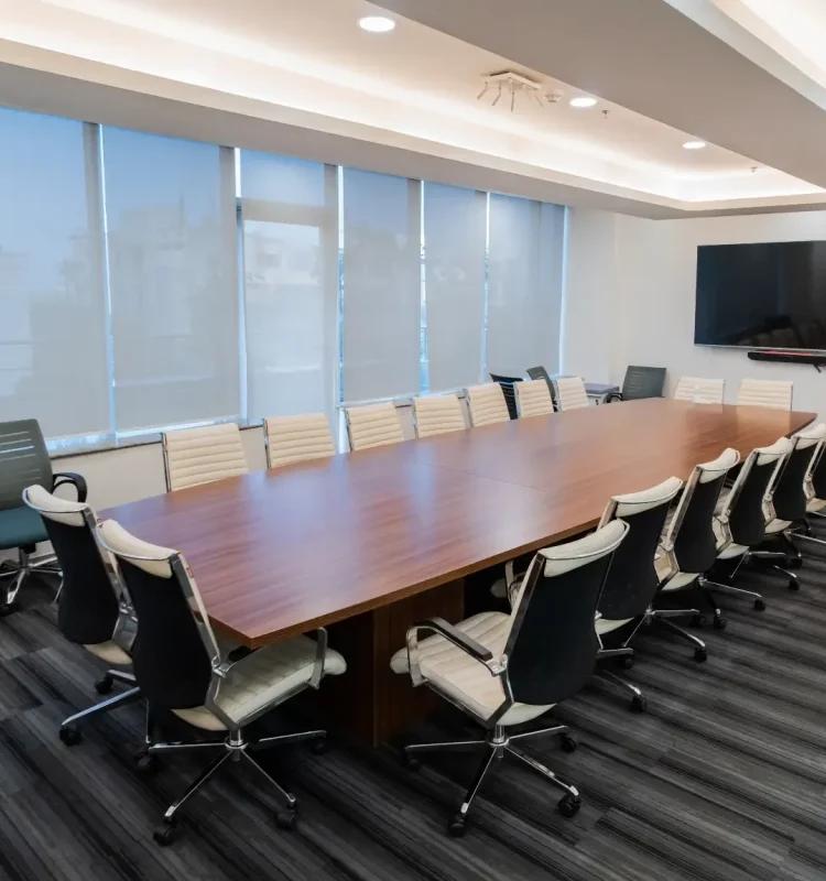 Boardroom with long wood table, cream leather chairs, wall screen and sheer-blind windows, AIHP Signature, Udyog Vihar Gurgaon