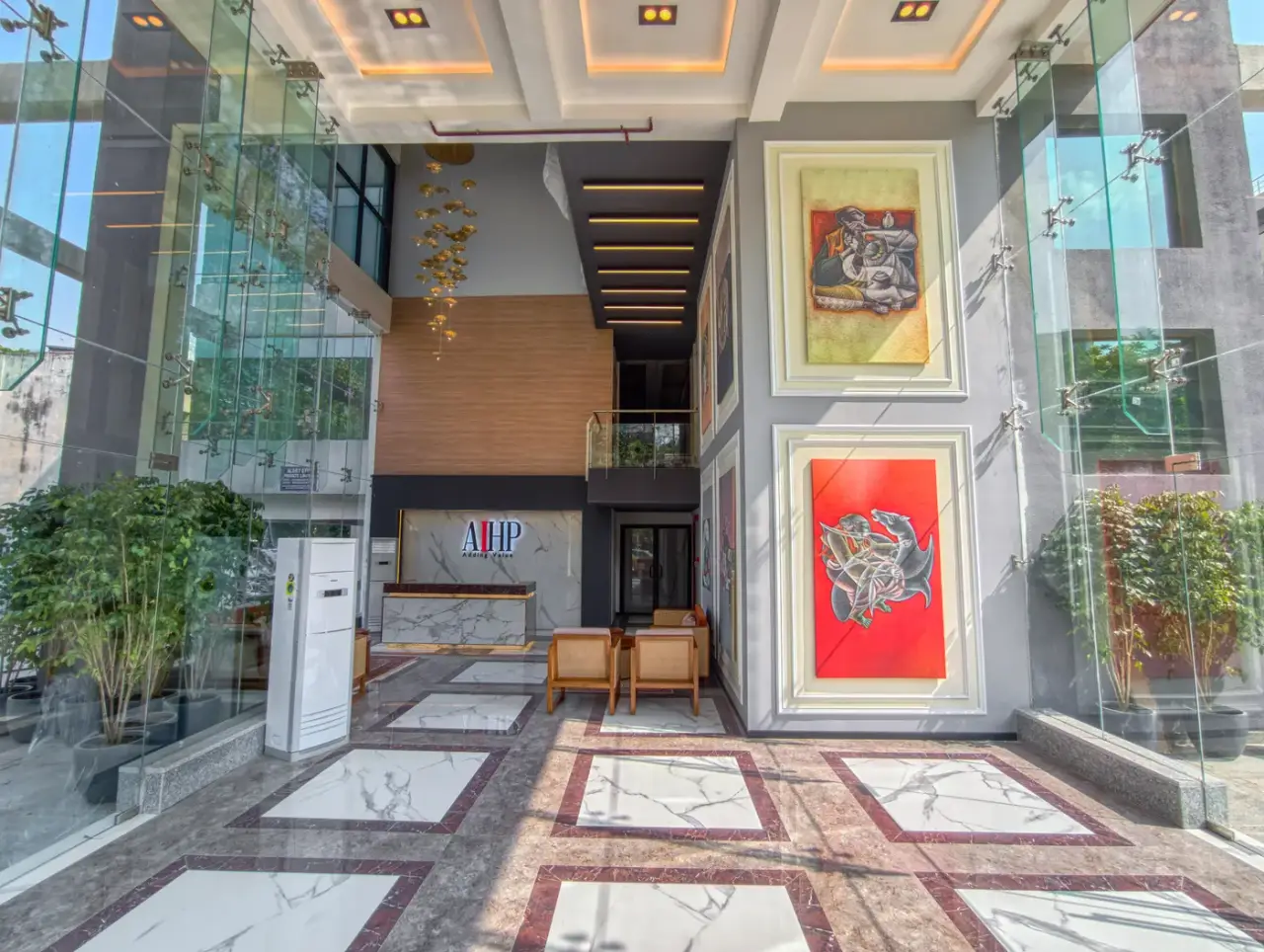 AIHP Atrium double-height lobby with a backlit art wall and AIHP signage over marble flooring, Sector 32, Gurgaon